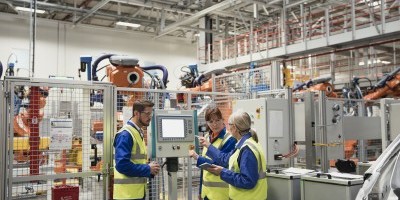 Group of factory workers using a control panel.