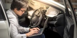 Young Asian Engineer or Architect working with laptop computer while sitting in his car. Mechanical engineering and building construction concepts